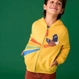 Child wearing the Frugi organic cotton blaire zip hoodie in bumblebee yellow with eagle applique with rust brown trousers. 