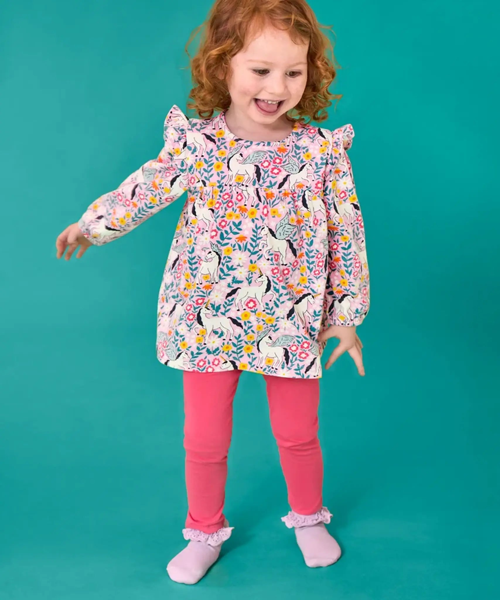 Child wearing the Frugi organic cotton Charlotte outfit. All over floral flight, frilled shoulder long sleeve top with rhubarb pink leggings.