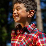 Child wearing the Frugi organic cotton festive check hector long sleeve shirt with chest pocket. Close up of collar.