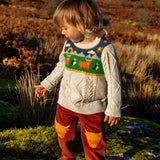 Child wearing Frugi clyde cable knit organic cotton jumper natural highlands cow and puffin design with rust highland cow corduroy trousers.