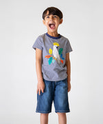 A child wearing the Frugi Elijah Applique T-Shirt - Navy Stripe / Cockatoo with denim shorts.