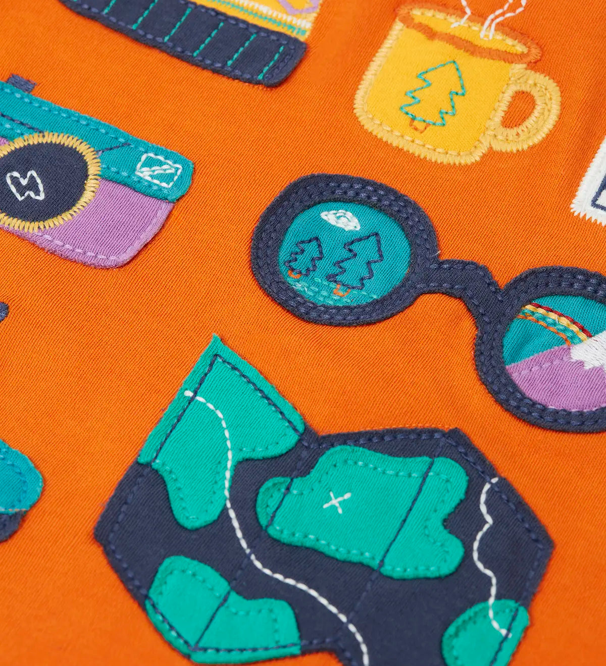 Close up of the details on the adventure themed appliques on the front of the Frugi compass hooded top in orange with turquoise arms and navy hood. 
