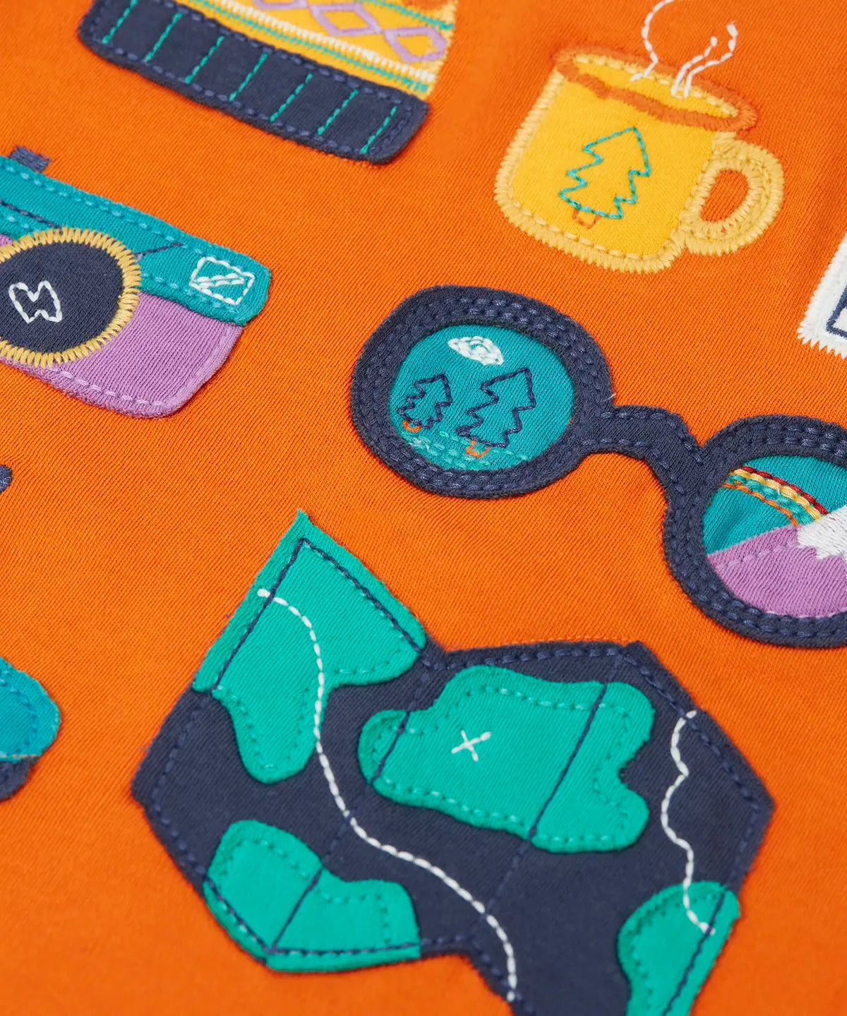 Close up of the details on the adventure themed appliques on the front of the Frugi compass hooded top in orange with turquoise arms and navy hood. 
