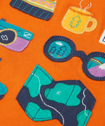 Close up of the details on the adventure themed appliques on the front of the Frugi compass hooded top in orange with turquoise arms and navy hood. 