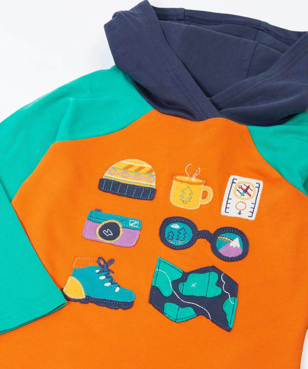 Close up of the adventure themed appliques on the front of the Frugi compass hooded top in orange with turquoise arms and navy hood. 