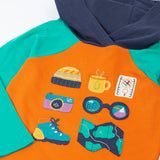 Close up of the adventure themed appliques on the front of the Frugi compass hooded top in orange with turquoise arms and navy hood. 