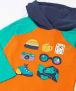 Close up of the adventure themed appliques on the front of the Frugi compass hooded top in orange with turquoise arms and navy hood. 