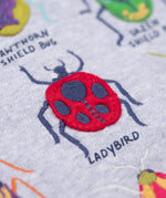 A close up of the ladybird embroidered applique on the Frugi compass hooded long sleeve bug design hoodie top.