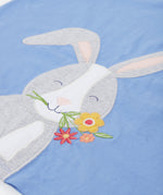 Close up of the Frugi kids cornflower blue rabbit appliqué t-shirt. Showing the appliqué detail of a grey rabbit head holding a bunch of flowers on light blue organic cotton fabric