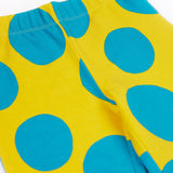 A close up of the Frugi kids cosy flared leggings in super spot showing the bold blue spot design on yellow organic cotton fabric.
