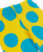 A close up of the Frugi kids cosy flared leggings in super spot showing the bold blue spot design on yellow organic cotton fabric.