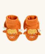 A pair of frugi orange corduroy baby booties designed to look like Highland cows, featuring yellow shaggy hair, white horns, and embroidered cow faces.