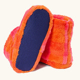 A pair of frugi fuzzy slipper boots in a bright orange and pink striped pattern, with one boot turned to show the dark blue textured non-slip sole.
