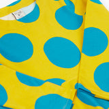 A close up of the Frugi cosy skater dress in super spot. Showing the bold blue dot print detail on yellow organic cotton fabric.