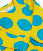 A close up of the Frugi cosy skater dress in super spot. Showing the bold blue dot print detail on yellow organic cotton fabric.