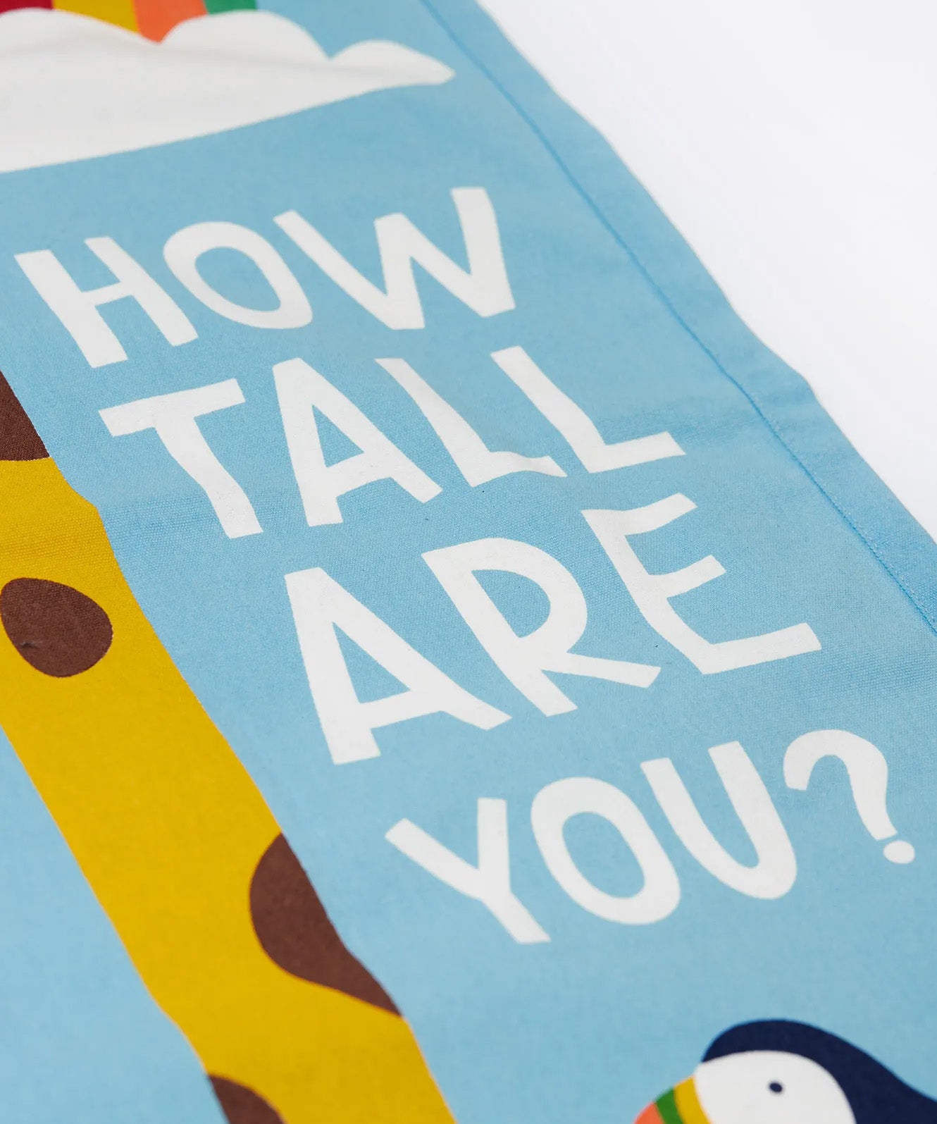 A closeup of the Frugi organic cotton wall decor height chart for kids, reading How tall are you?' in white Frugi font.