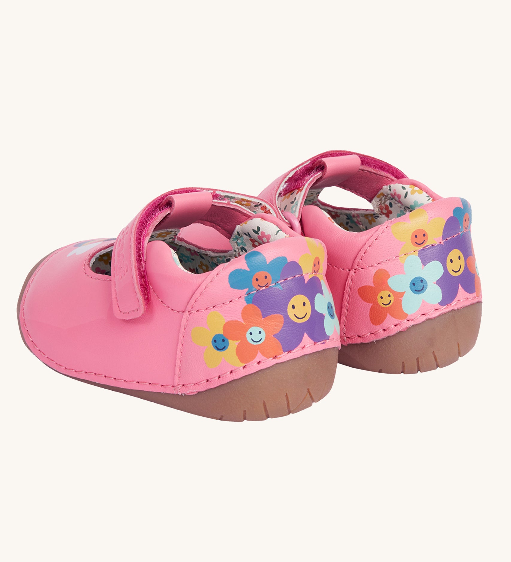 An images of the back of the Frugi cove first walker t-bar style shoes with a bee and tulip design. The back of the shoes have a colourful flower design with happy faces on them.