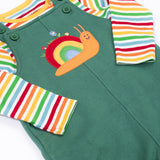 A close up of the Frugi kids coverack dungaree outfit in holly green/snail showing the playful snail applique and button fastener detail with the striped top underneath