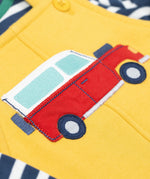 A close up of the Frugi kids coverack dungaree outfit in bumblebee/vehicle showing the red vehicle applique detail on yellow organic cotton fabric.