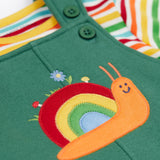 A close up of the Frugi kids coverack dungaree outfit in holly green/snail showing the playful snail applique detail on green organic cotton fabric.