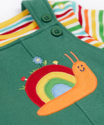 A close up of the Frugi kids coverack dungaree outfit in holly green/snail showing the playful snail applique detail on green organic cotton fabric.