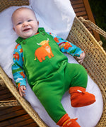 Baby wearing the Frugi coverack palm green dungaree with highland coos applique with a highland cows design long sleeve body underneath. 