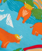 Frugi kids dungaree outfit showing a close up of the repeating highland cow print on the light blue organic cotton top 