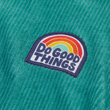 Close up of the do good things rainbow badge on the chest of the Frugi Croft organic cord half zip jumper in hut green.