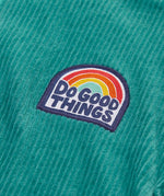 Close up of the do good things rainbow badge on the chest of the Frugi Croft organic cord half zip jumper in hut green.