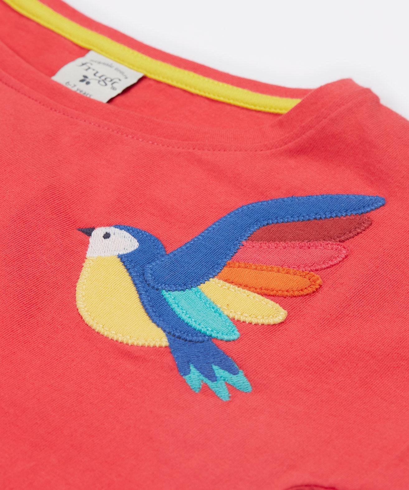 A close up of Frugi Daisy Applique T-Shirt in Watermelon's embroidered colourful parrot.