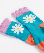A close up of the Frugi kids Freya sock. Showing the light blue sock with white daisy design and light purple frill on organic cotton fabric.