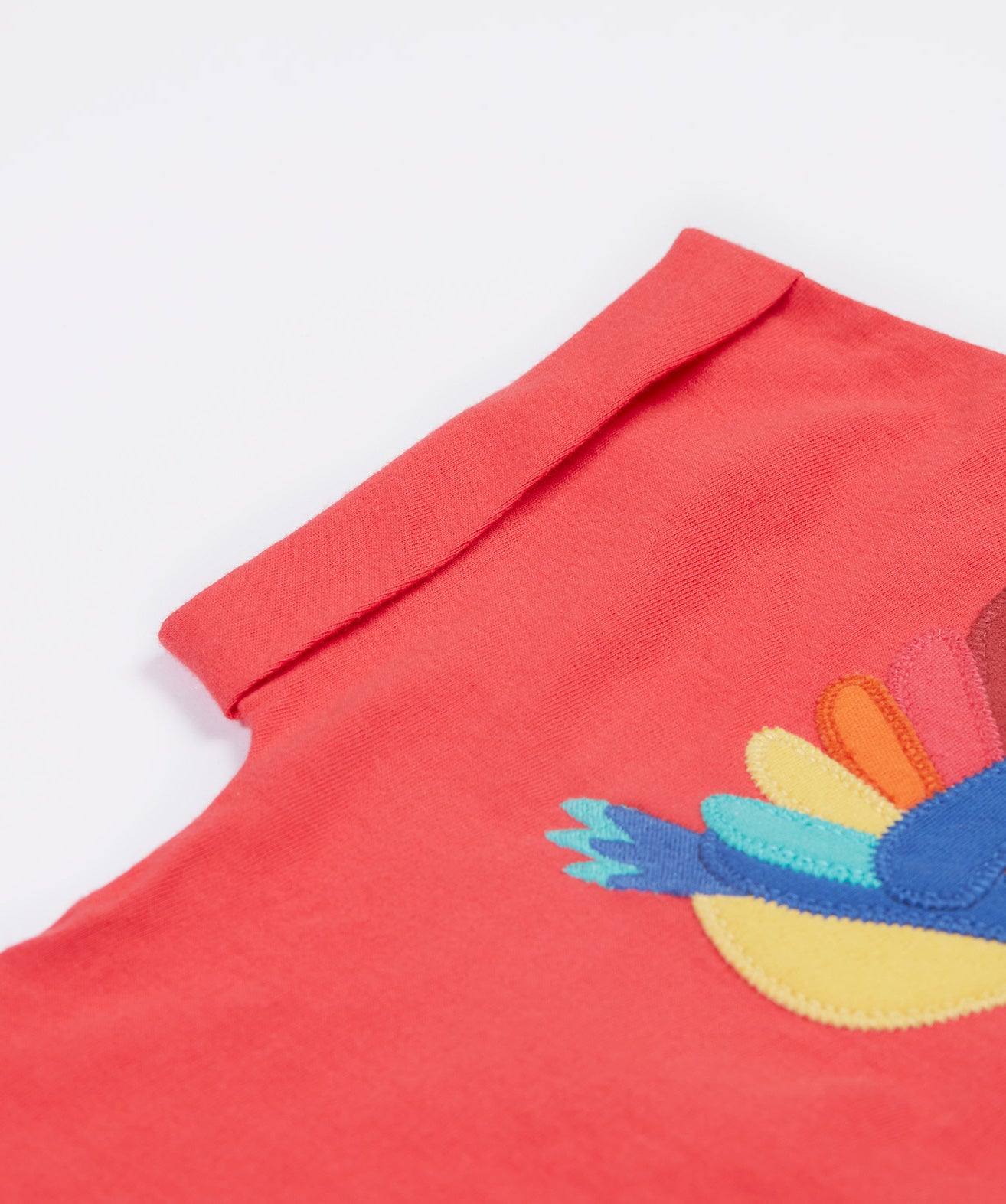 A close up of the Frugi Daisy Applique T-Shirt in Watermelon's folded sleeve.