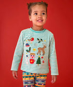 A young child wearing a Frugi organic cotton long-sleeve striped top with a festive Christmas-themed applique design and knitted fair isle leggings.