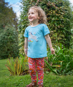 A child wearing the Frugi Libby leggings, a soft pink GOTS organic cotton leggings with a donkey and flower design.