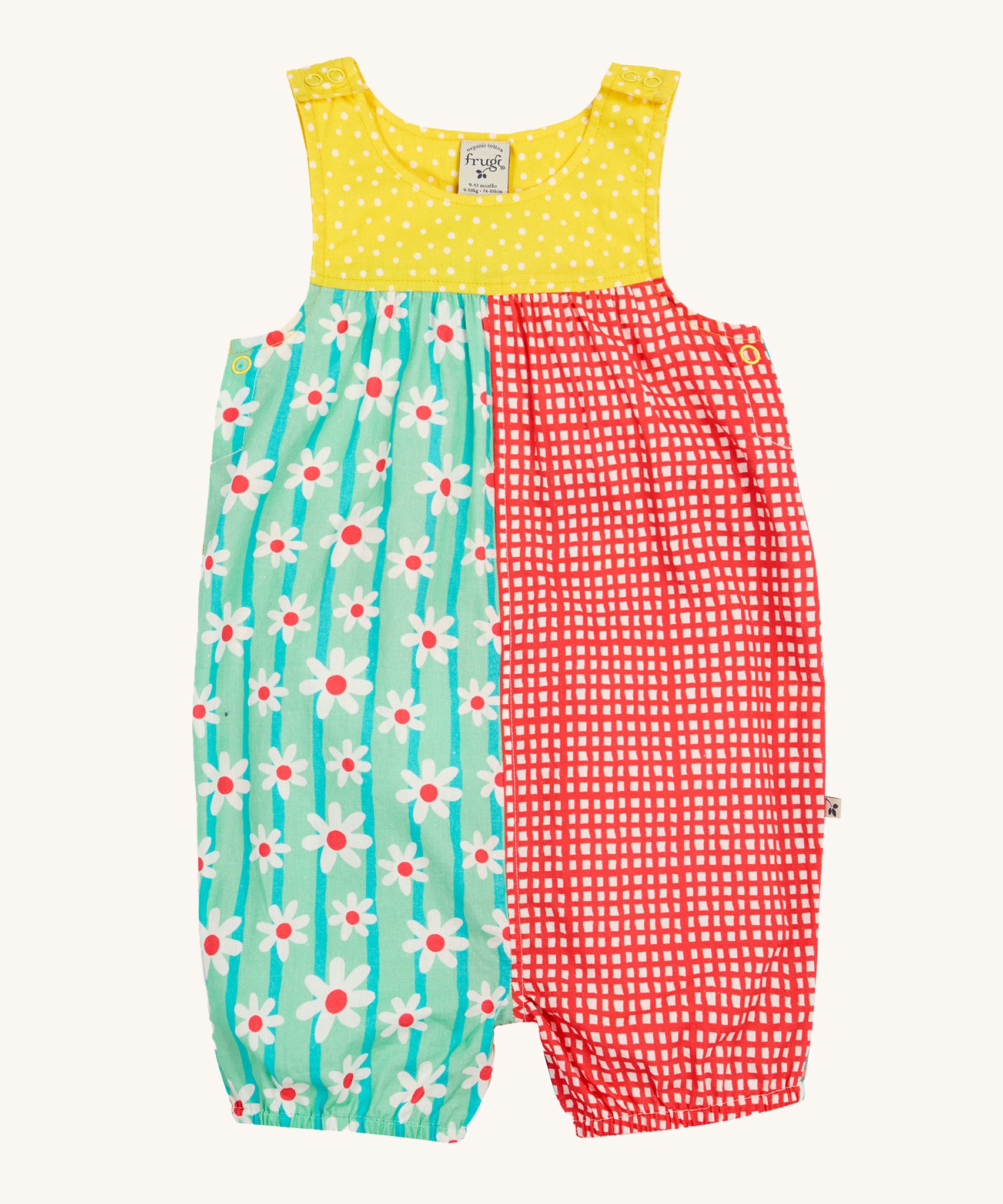 Frugi Summer Printed Dungaree in the Rainbow Hotchpotch print laid flat, showing a patchwork type design in yellow, red and green with daisies, featuring popper fastenings.