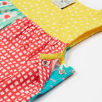 A close up of the popper fastenings on the Frugi Summer Printed Dungaree in the Rainbow Hotchpotch print.