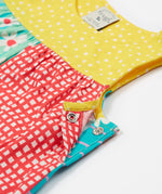 A close up of the popper fastenings on the Frugi Summer Printed Dungaree in the Rainbow Hotchpotch print.