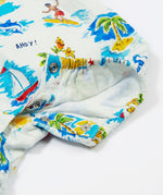 A close-up of the Frugi Aloha Organic Cotton Dungarees popper fastenings, featuring a colourful tropical beach print with dolphins, rainbows and sailing boats.