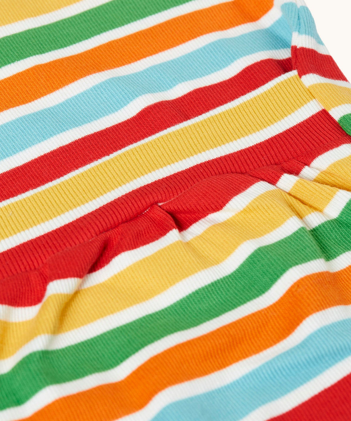 A close up of the easy access at the back of the Frugi easy dressing rainbow striped ribbed material babygrow. easy access on the back to roll off the legs off for easy nappy changes. 