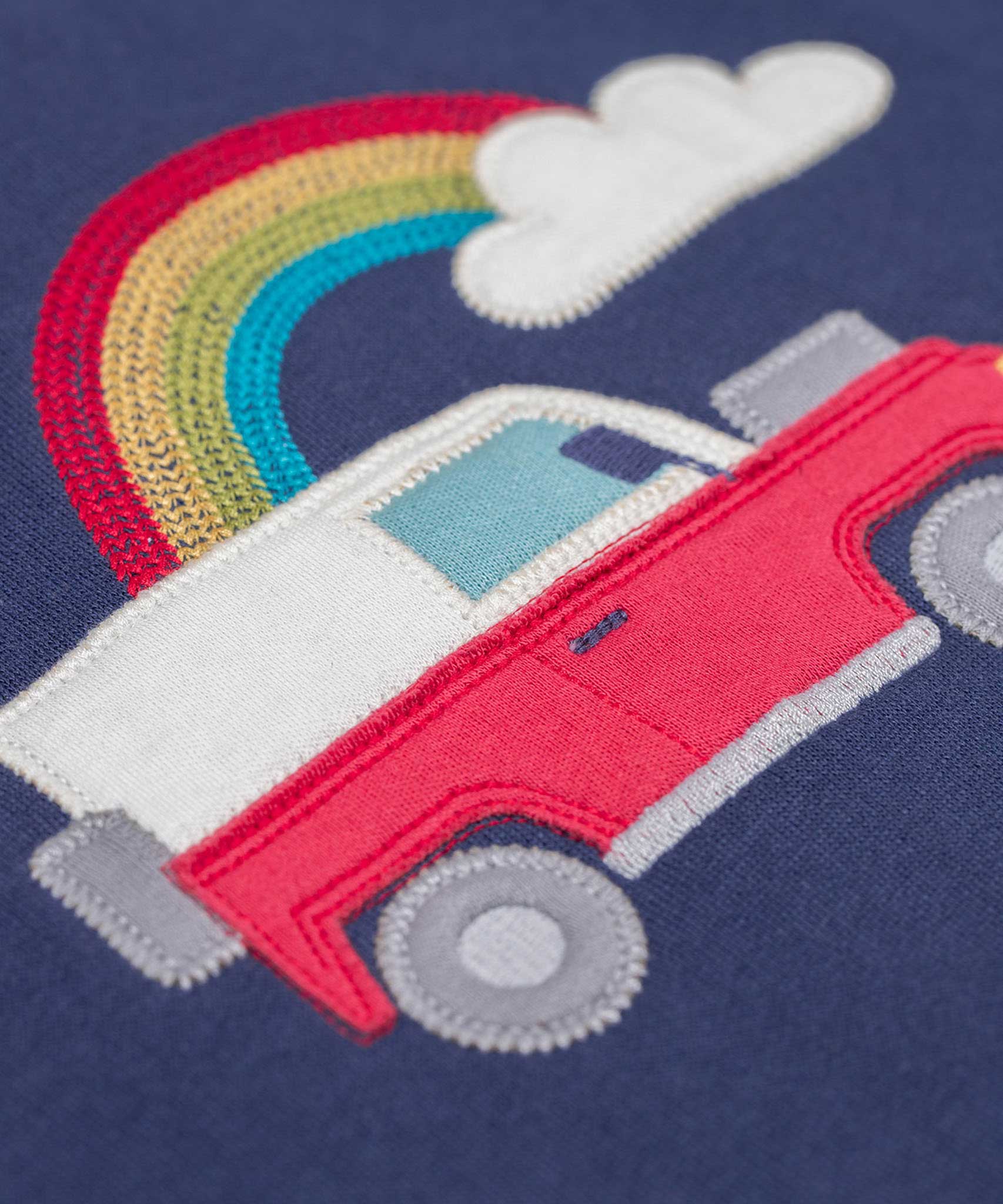 A close up of the red landy type vehicle applique on the front of the Frugi easy on organic cotton navy jumper.