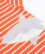 A close up of Frugi Elijah Wrap Around T-Shirt in Orange Stripe's embroidered shark.