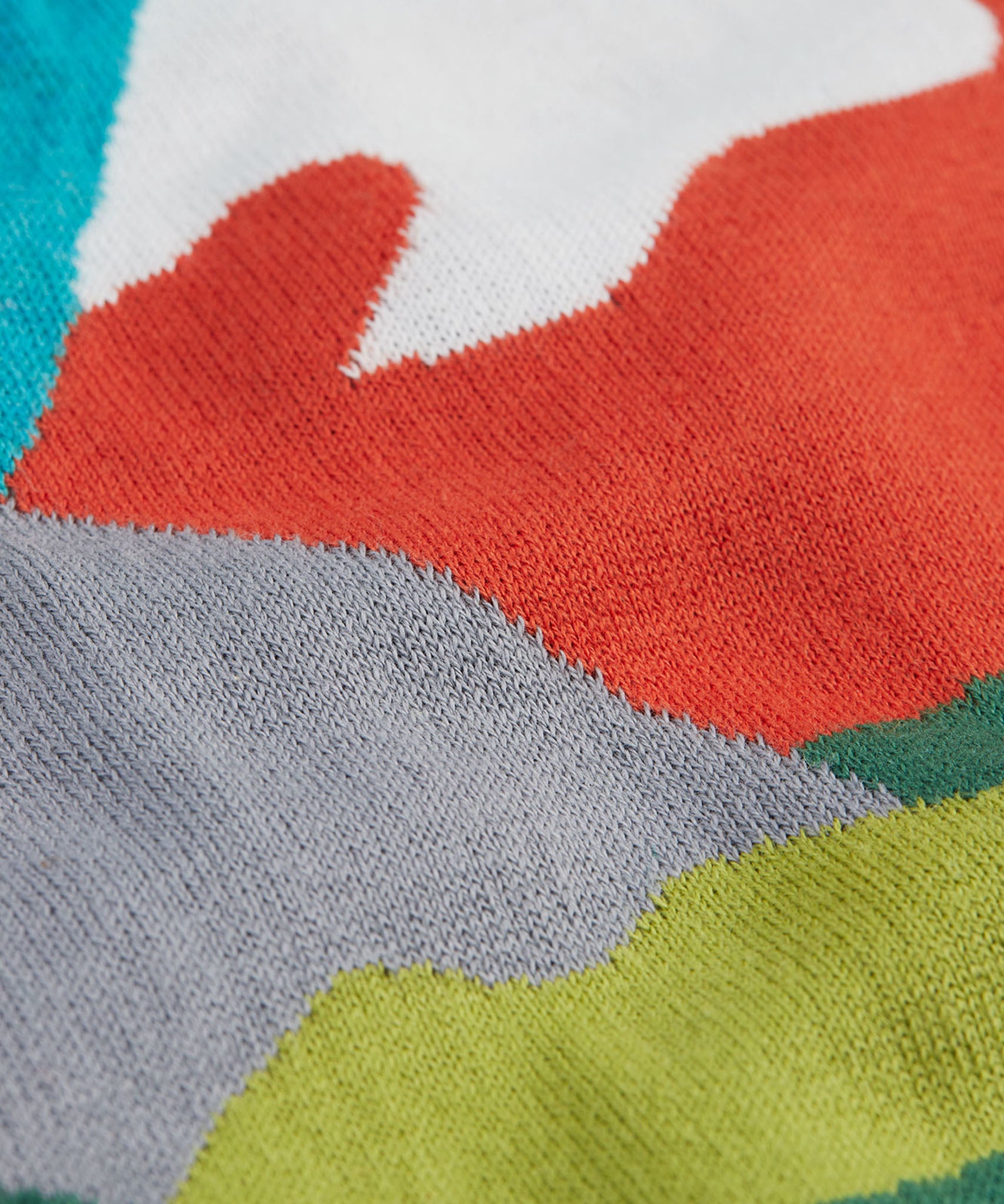 A super close view of the Frugi Elwood organic cotton knitted jumper with a blue mountain scene design showing the material.
