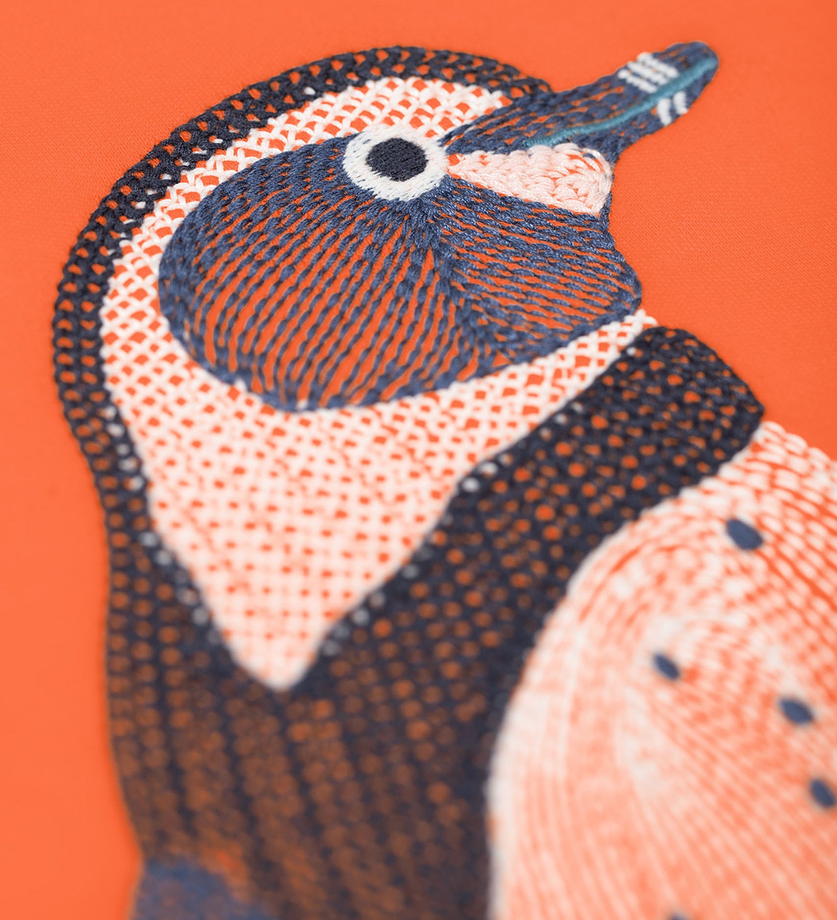 A close up of the Frugi kids embroidered adventure top in salamander/penguin showing the embroidery detail on pastel orange organic cotton fabric.