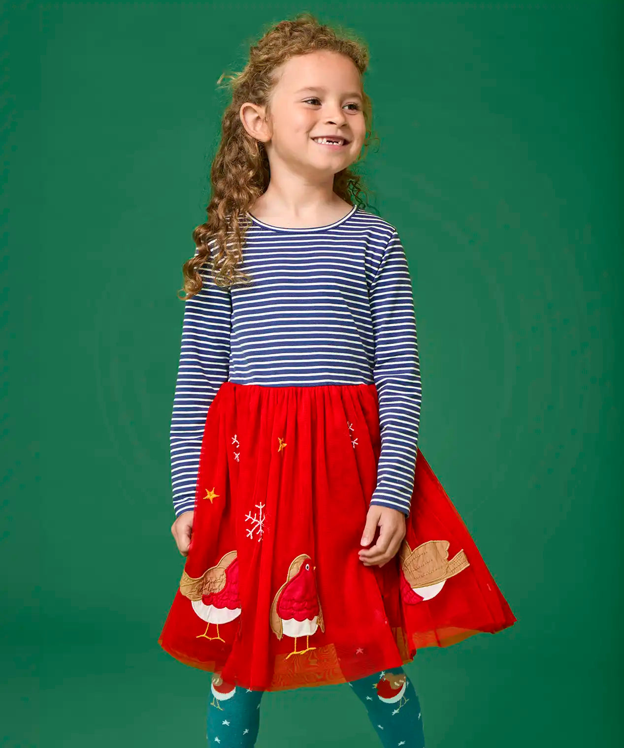 Child wearing the Frugi emmie skater dress with a long sleeved navy stripe top half and red robin applique tulle  skirt.