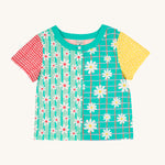 Frugi Estella Shirt laid flat, with a Rainbow Hotchpotch print, a patchwork type design in red, mint, green and yellow with daisies and white buttons down the middle.