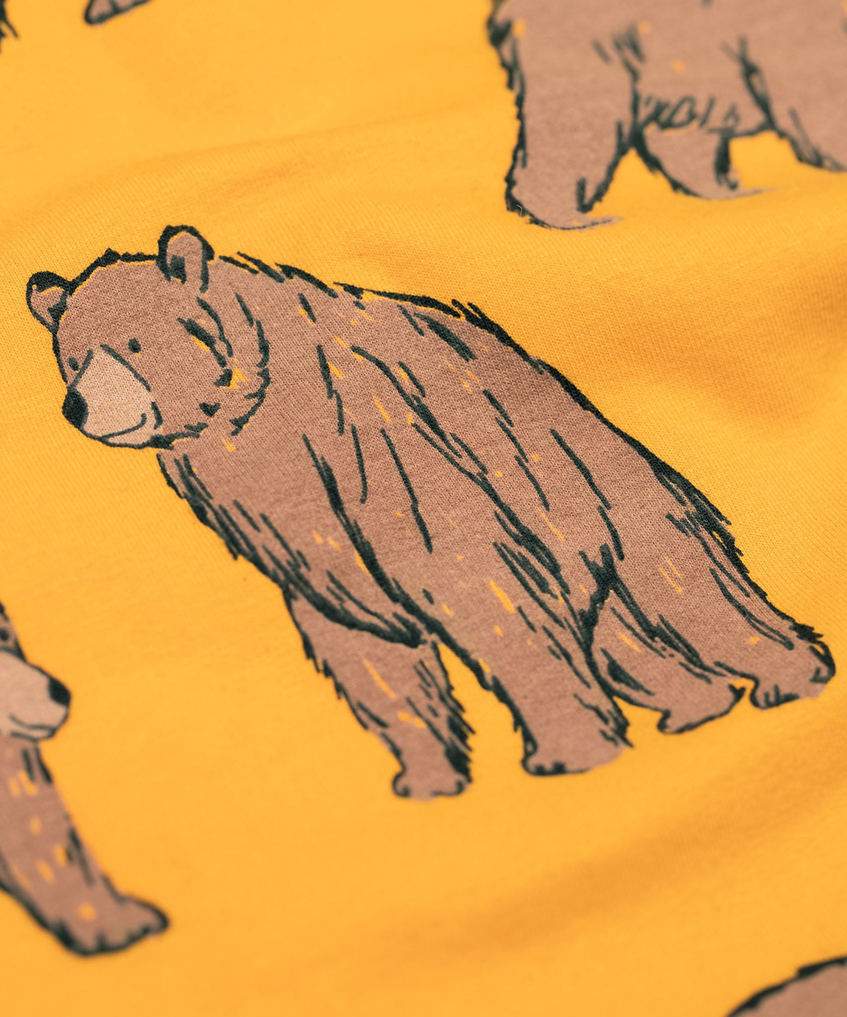 A close up of the Frugi kids Ethan printed sweater in beary wild. Showing the brown bear print detail on dark yellow organic cotton fabric.