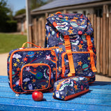 Frugi trail blazing backpack, lunch bag and matching pencil case in the explore the stars design placed on a blue picnic table.