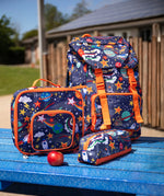 Frugi trail blazing backpack, lunch bag and matching pencil case in the explore the stars design placed on a blue picnic table.
