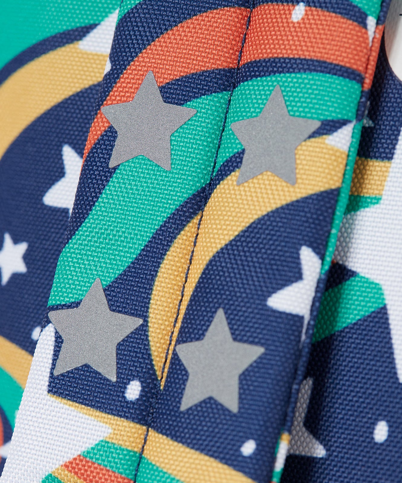 A close up of the shoulder strap on the Frugi magic stars explorer backpack showing the reflective stars detail. 