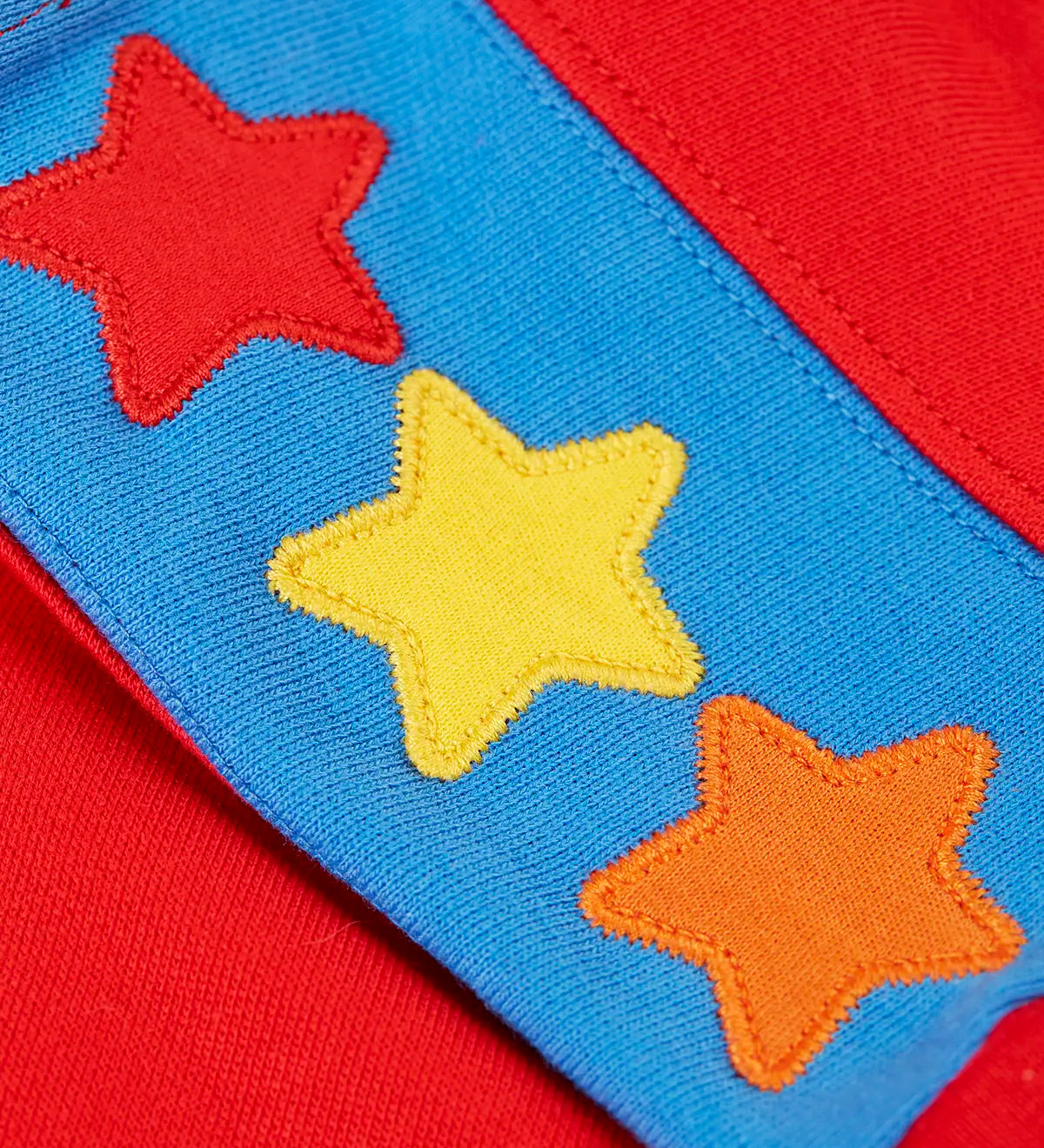 Close up of the three star appliques on the shoulders of the Frugi Falmouth scarlet red sweatshirt.